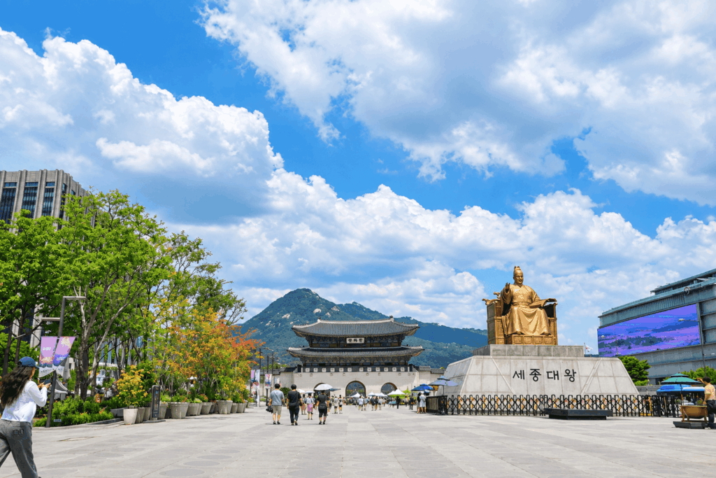 Gwanghwamun Gate and King Sejong Statue under dramatic summer clouds in Seoul, South Korea.