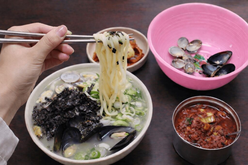 Seafood kalguksu broth with clams and green onions at Chanyangjip