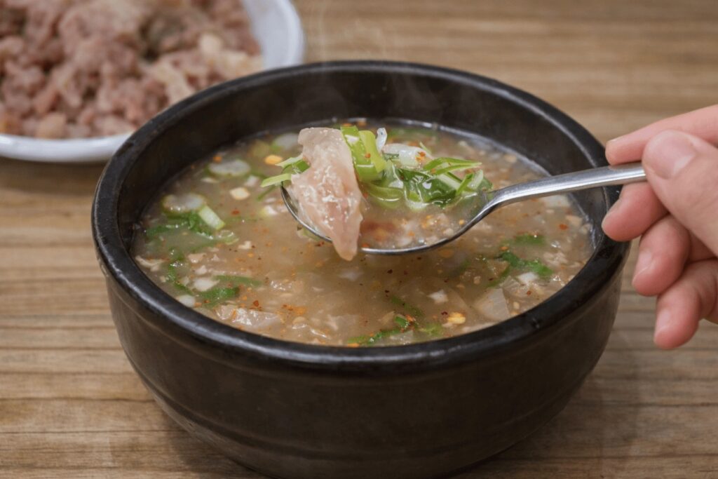 Spoon lifting beef cartilage from dogani tang Korean soup close-up texture