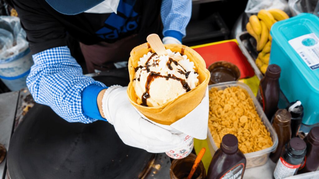 Fresh strawberry banana crepe with vanilla ice cream and chocolate syrup at a Dongdaemun street food stall in Seoul