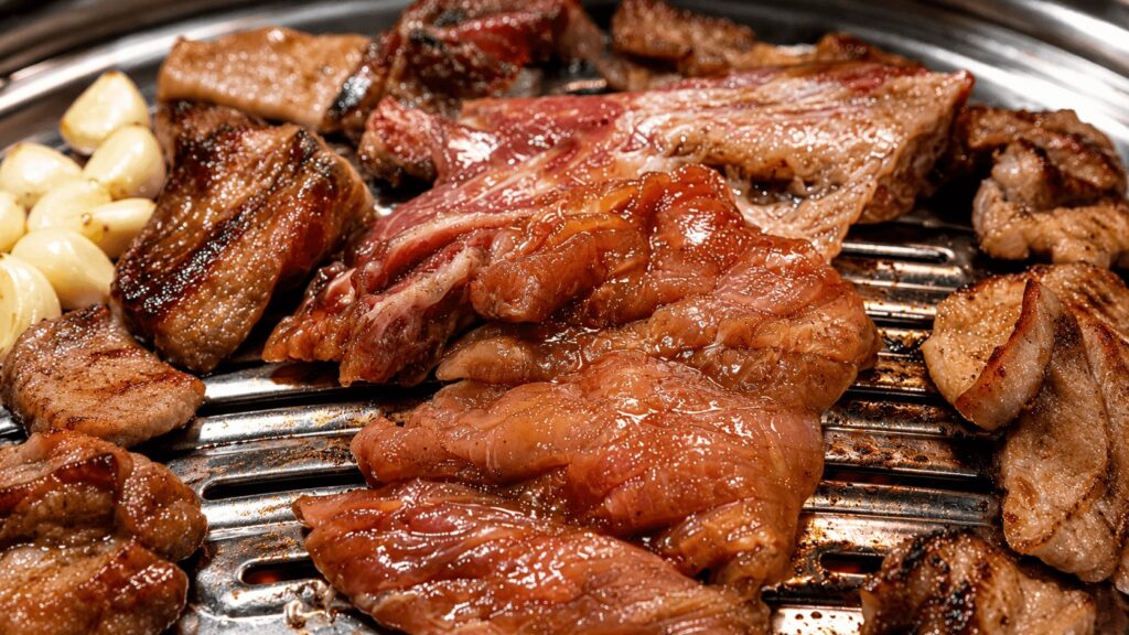 Marinated Korean pork galbi cooking on a tabletop grill