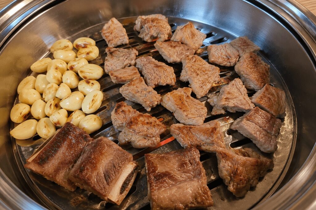 Grilled pork galbi and garlic cooking on a Korean BBQ grill