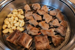 Grilled pork galbi and garlic cooking on a Korean BBQ grill