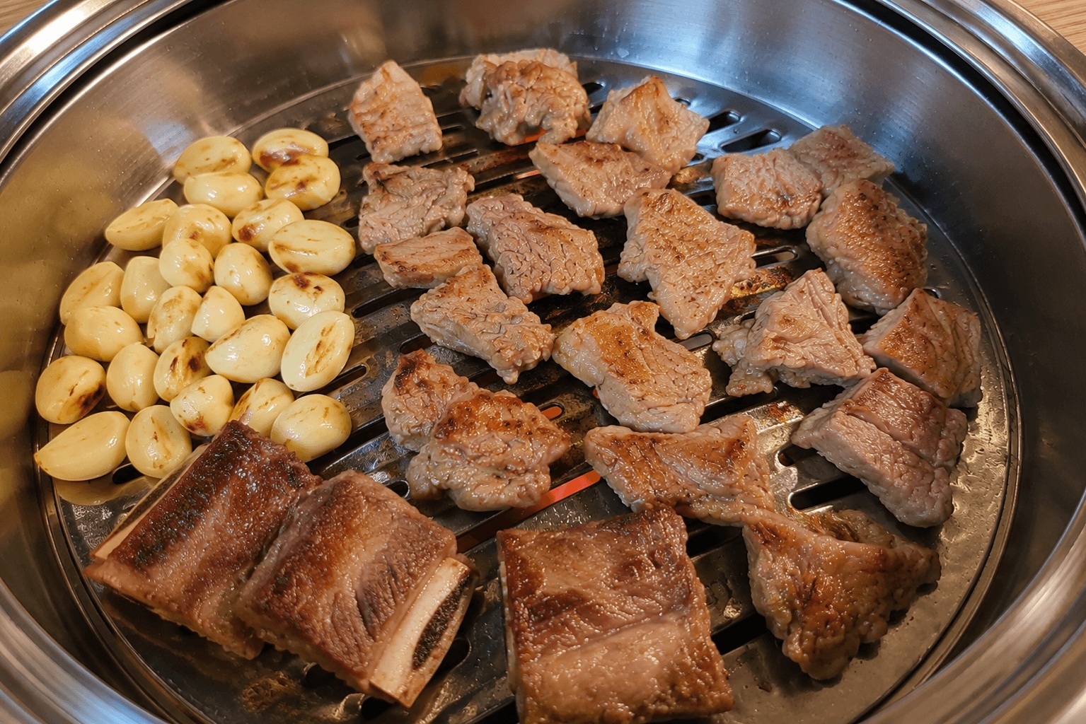 Grilled pork galbi and garlic cooking on a Korean BBQ grill