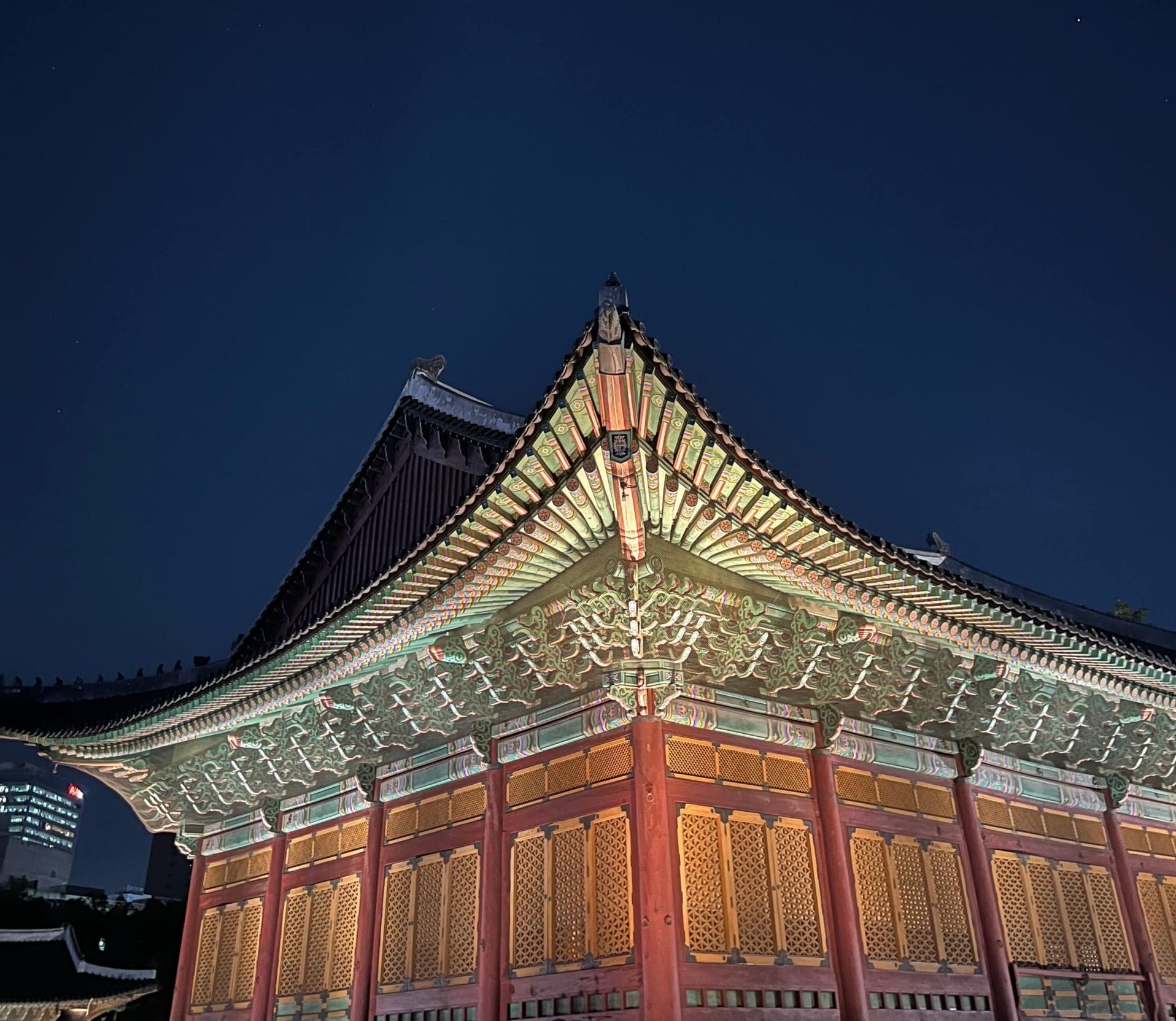 Ornate roof of a Deoksugung palace building illuminated at night