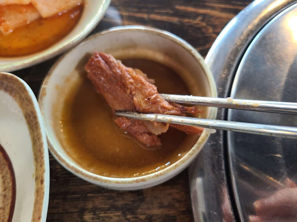 Pork meat dipped in savory sauce at a gamjatang restaurant in Seongsu