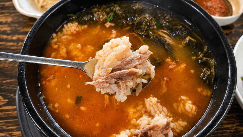 Spoon of rice and pork from spicy gamjatang soup in Seongsu